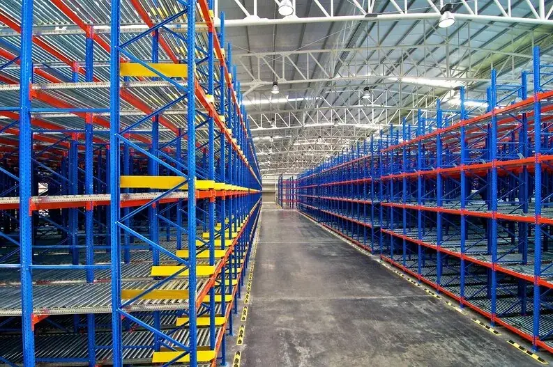 Empty warehouse aisle between tall blue and orange pallet racks